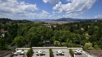 A rooftop terrace with outdoor seating, overlooking a cityscape with mountains in the distance.