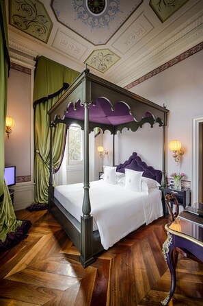 A four-poster bed with a purple canopy, a wooden floor, and a decorative ceiling.
