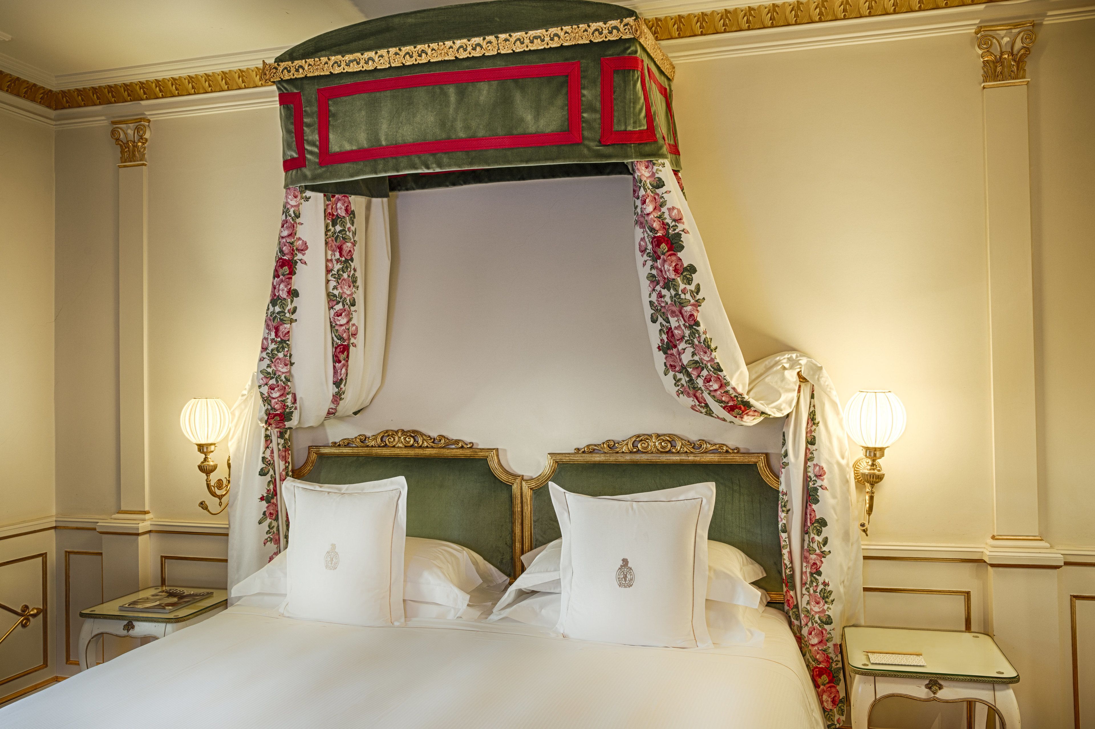 A four-poster bed with a canopy, two bedside tables, and wall-mounted lamps.