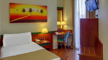 A hotel room with a bed, desk, chair, TV, and a painting on the wall.
