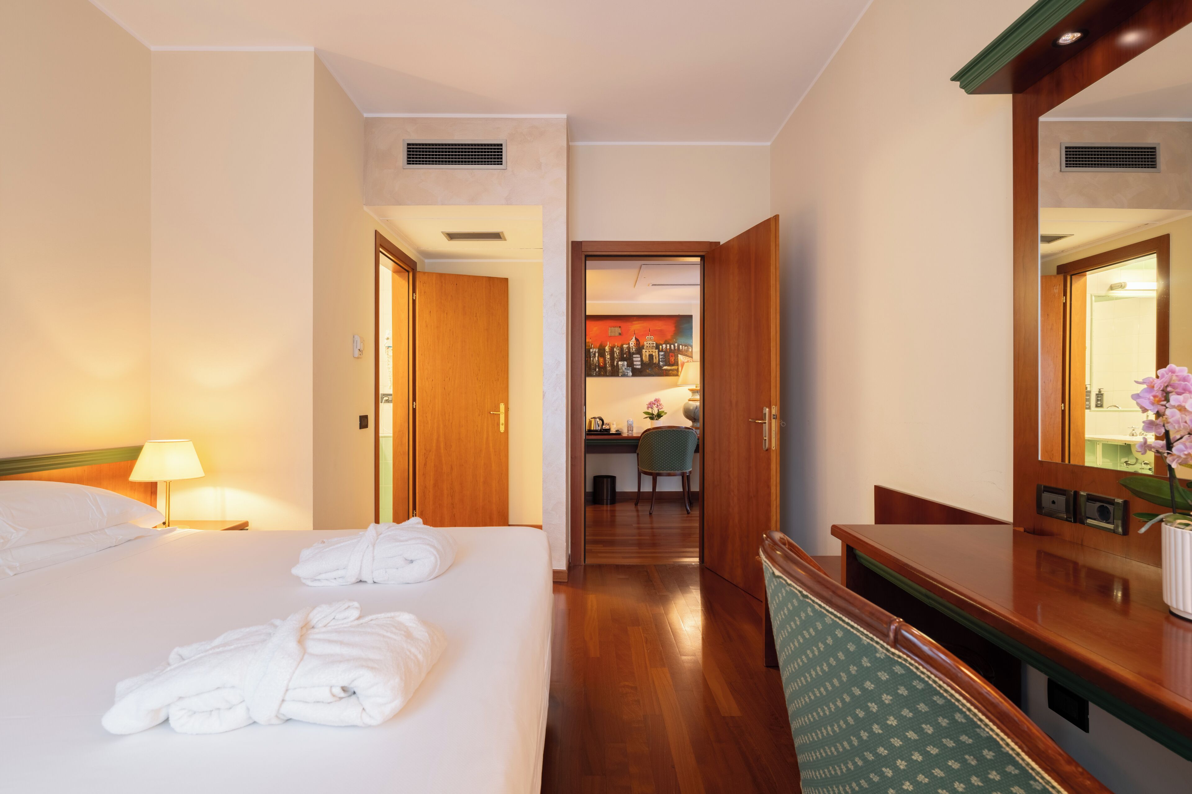 A hotel room with a bed, a desk, and a mirror.