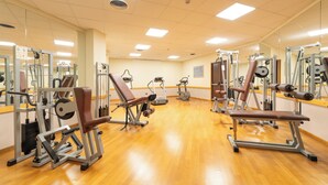 A gym with various exercise machines, mirrors, and a wooden floor. - Hotel Raffaello (Milan)