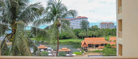 Un hotel con piscina, palmeras y vistas a un lago.
