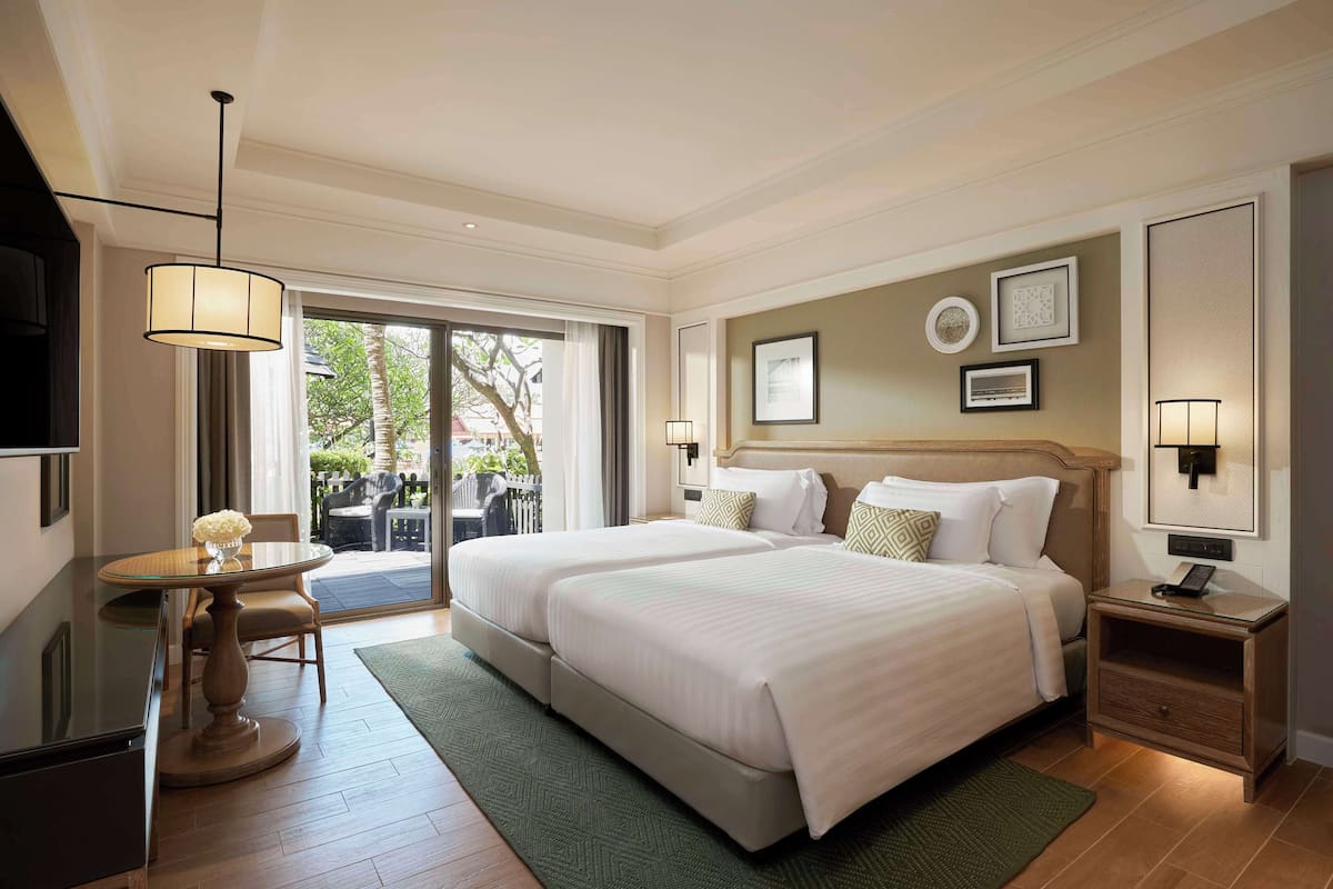 Habitación de hotel con dos camas, una mesa de comedor y un televisor.
