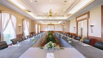 Un salón de conferencias con una larga mesa, sillas y una araña.