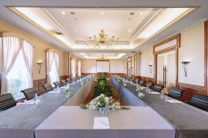 Un salón de conferencias con una larga mesa, sillas y una araña.
