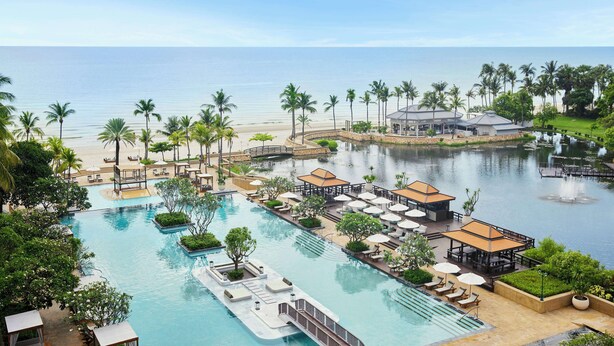 A resort with a large swimming pool, lounge areas, and a view of the ocean. - Dusit Thani Hua Hin (Cha-am)