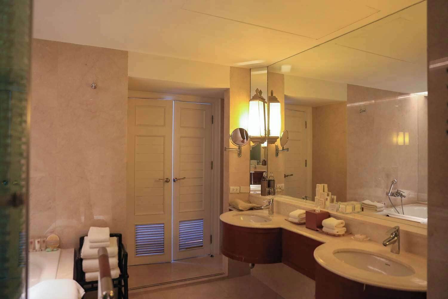 A modern bathroom with two sinks, a large mirror, and a shower area.