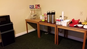 A small kitchenette with a microwave, a coffee maker, a kettle, and various food items on the counter. - Rapids Inn and Suites (Wisconsin Rapids)