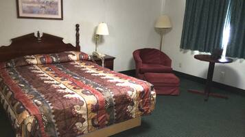 Ein Hotelzimmer mit einem großen Bett, einem Sessel, einem Schreibtisch, einer Lampe und einem Gemälde an der Wand.
