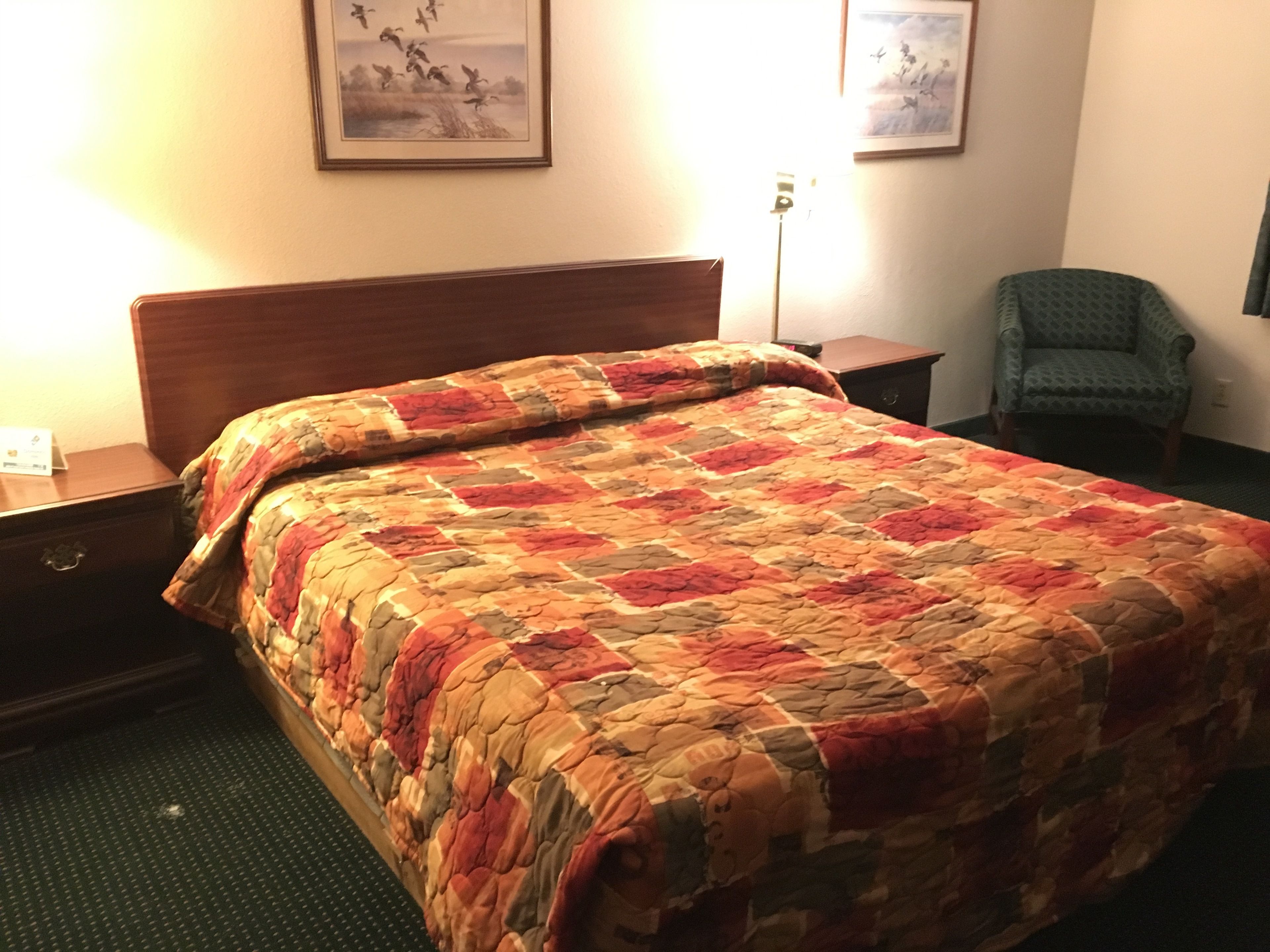 A hotel room with a bed, a chair, and a nightstand.