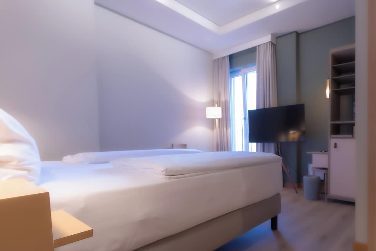 Una habitación de hotel con cama, televisión, escritorio y armario.