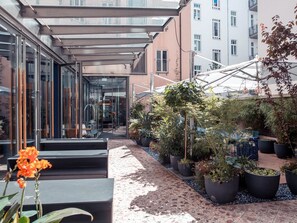 Een modern buitengebied met glazen wanden, plantenbakken en zitplaatsen.