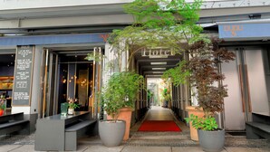A hotel entrance with a red carpet, potted plants, and a sign reading "BLEIBTREU".