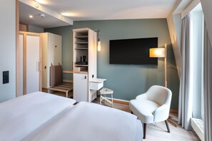 Une chambre d’hôtel avec deux lits, un bureau, une chaise, une télévision et une armoire.