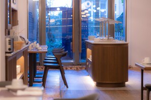 A modern interior with a counter, chairs, and a view through large windows.