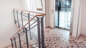 A modern interior with a glass railing, a tiled floor, and an elevator.