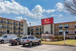 A hotel with a prominent sign for EconoLodge Inn & Suites, featuring a multi-story building with balconies and a parking lot with several cars.