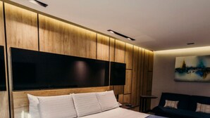 A modern hotel room with a large bed, a wooden headboard, a flat-screen TV, and a painting on the wall. - Hotel Araiza Mexicali (Mexicali)