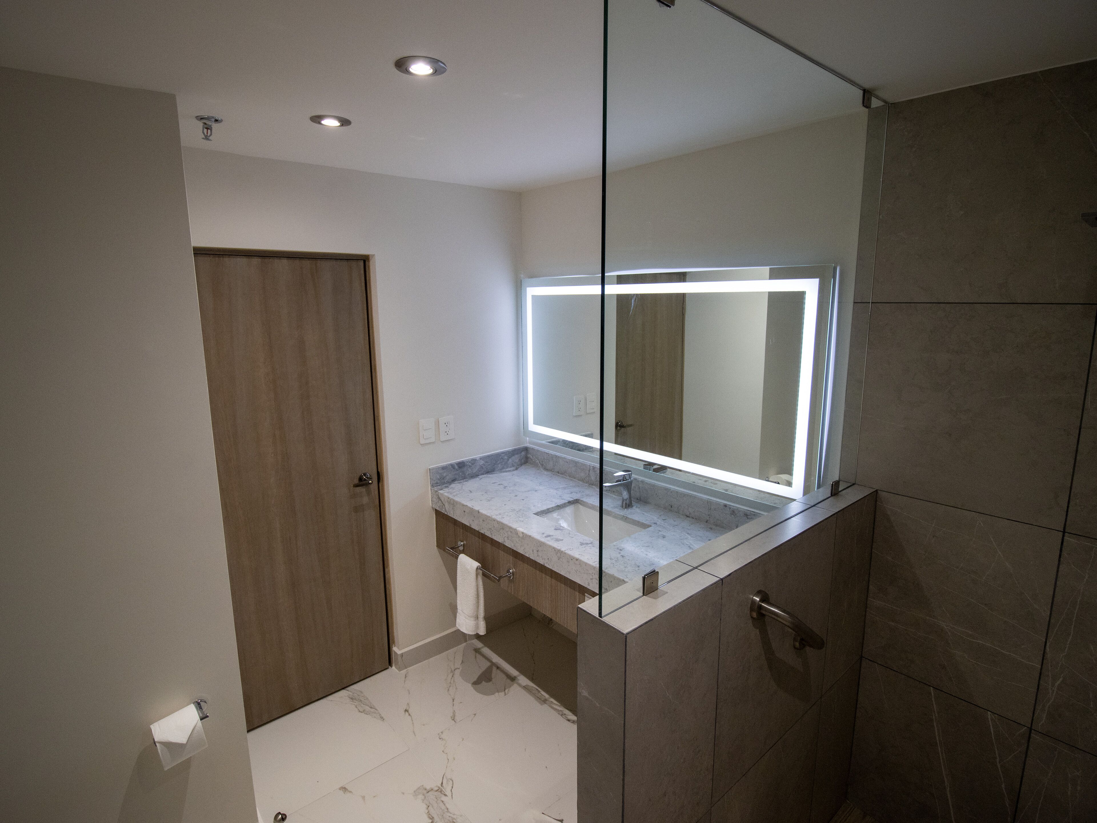 Ein modernes Badezimmer mit einem großen Spiegel, einer Dusche und einer Toilette.