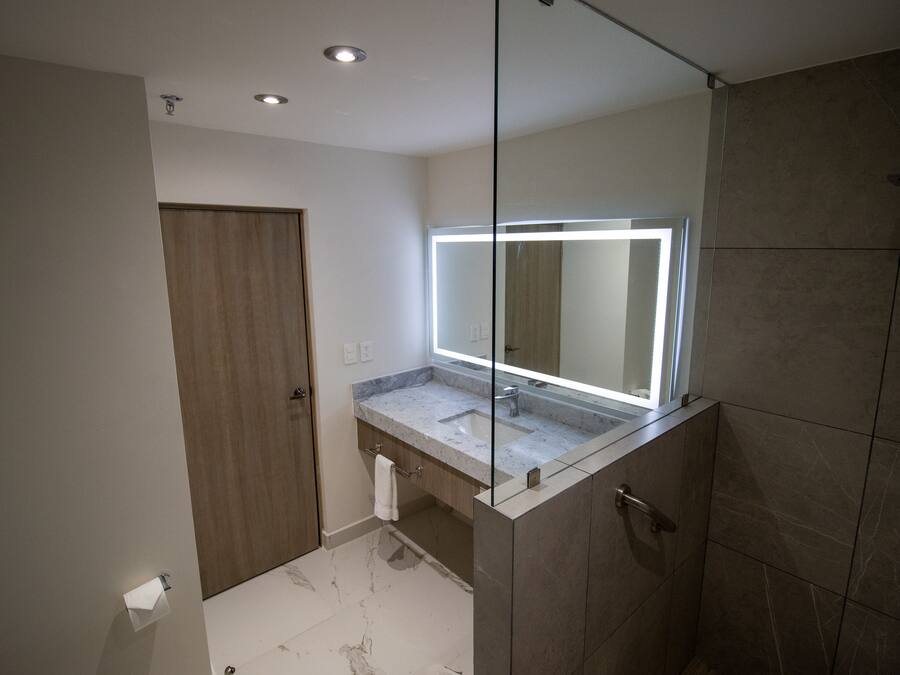 A modern bathroom with a large mirror, a shower, and a toilet.