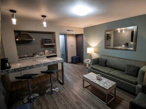 A compact living space with a kitchenette, a sofa, a coffee table, and a mirror.
