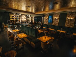 Een bar met zitplaatsen, een toog en een scherm aan de muur.