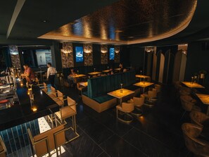 A dimly lit bar area with a counter, seating, and a decorative ceiling.