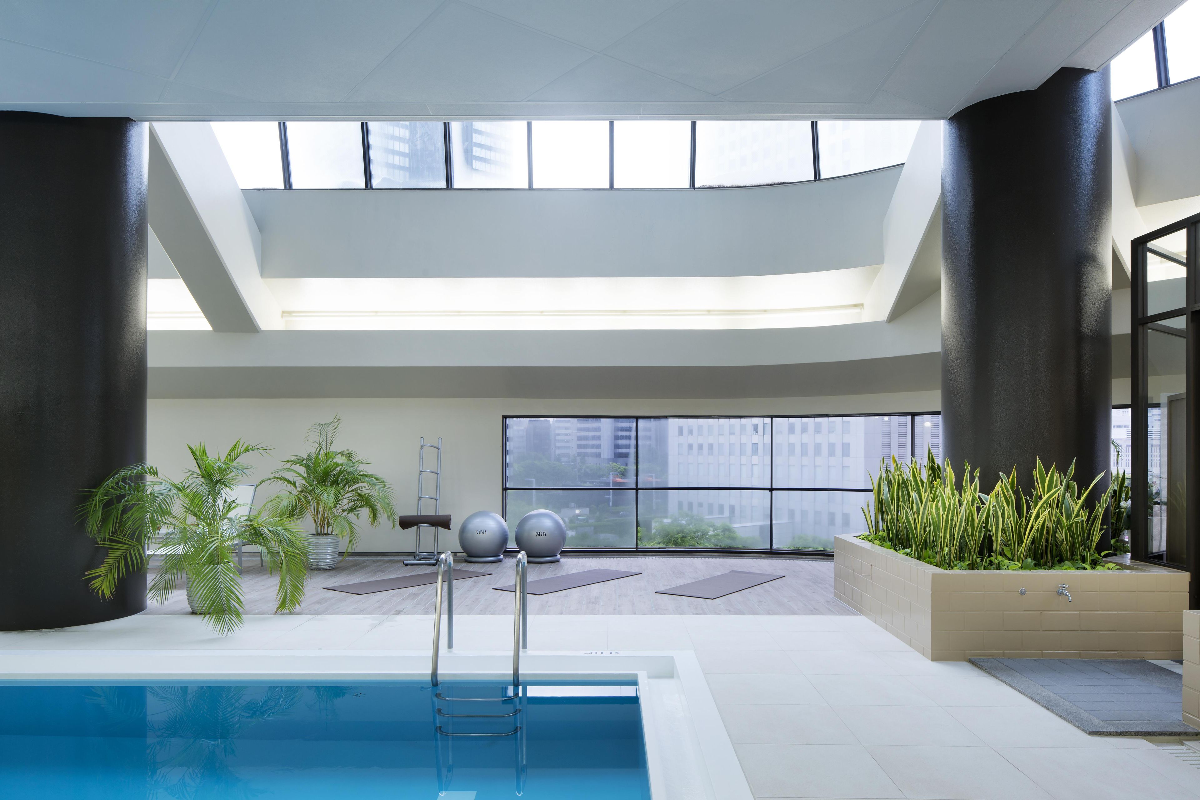 An indoor swimming pool with a view of the city through large windows.
