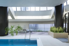 An indoor swimming pool with a view of the city through large windows.