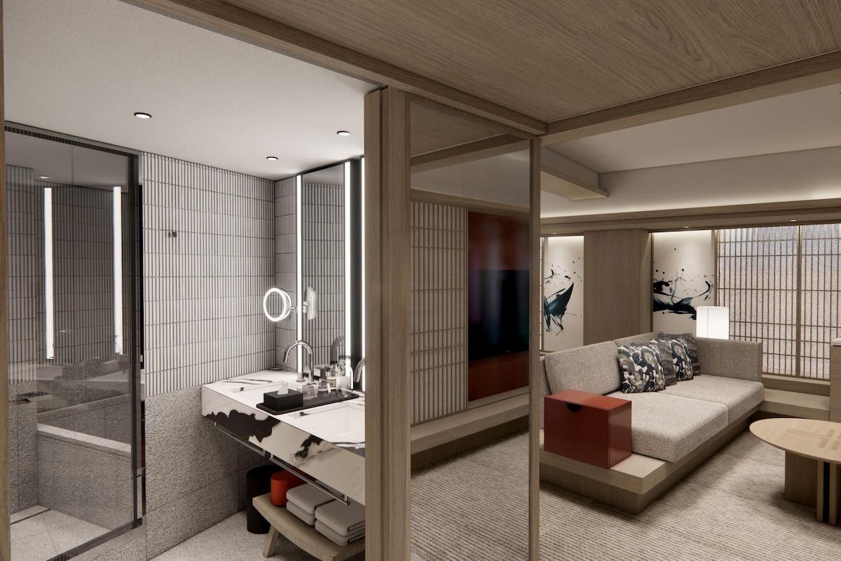 Een moderne hotelkamer met een grote spiegel, een wastafelmeubel, een bank met kussens, een klein tafeltje en kunst aan de wanden.