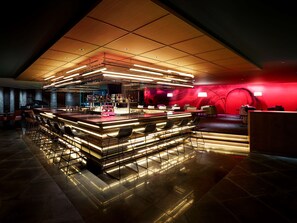 A modern bar area with a high ceiling and ambient lighting.