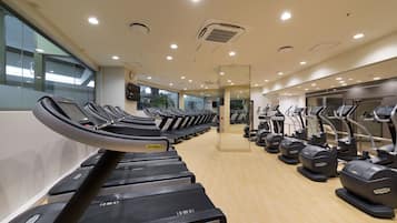 A gym with multiple treadmills and elliptical machines arranged in rows.