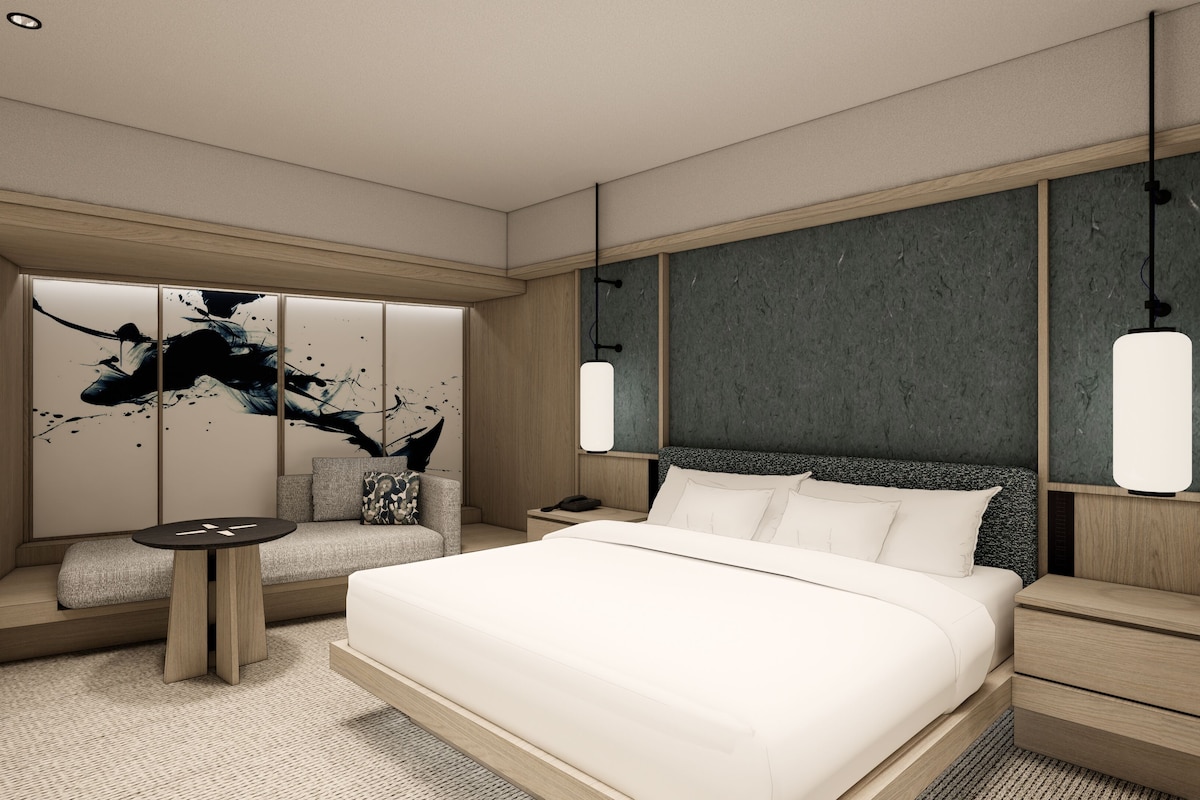 Een moderne hotelkamer met een groot bed, een zithoek en een bureau.
