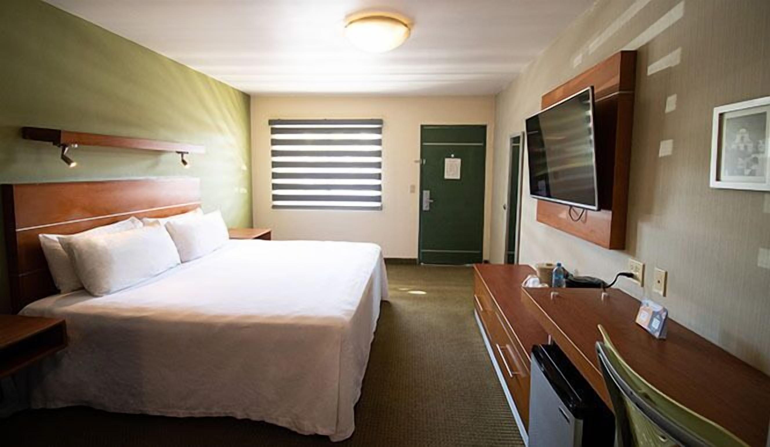 Una habitación de hotel con cama, televisión, escritorio y baño.