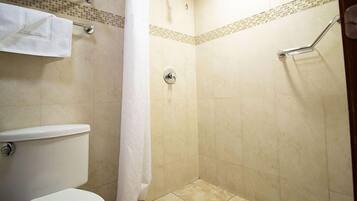 Un baño con inodoro, ducha con puerta de cristal y un perchero para toallas.