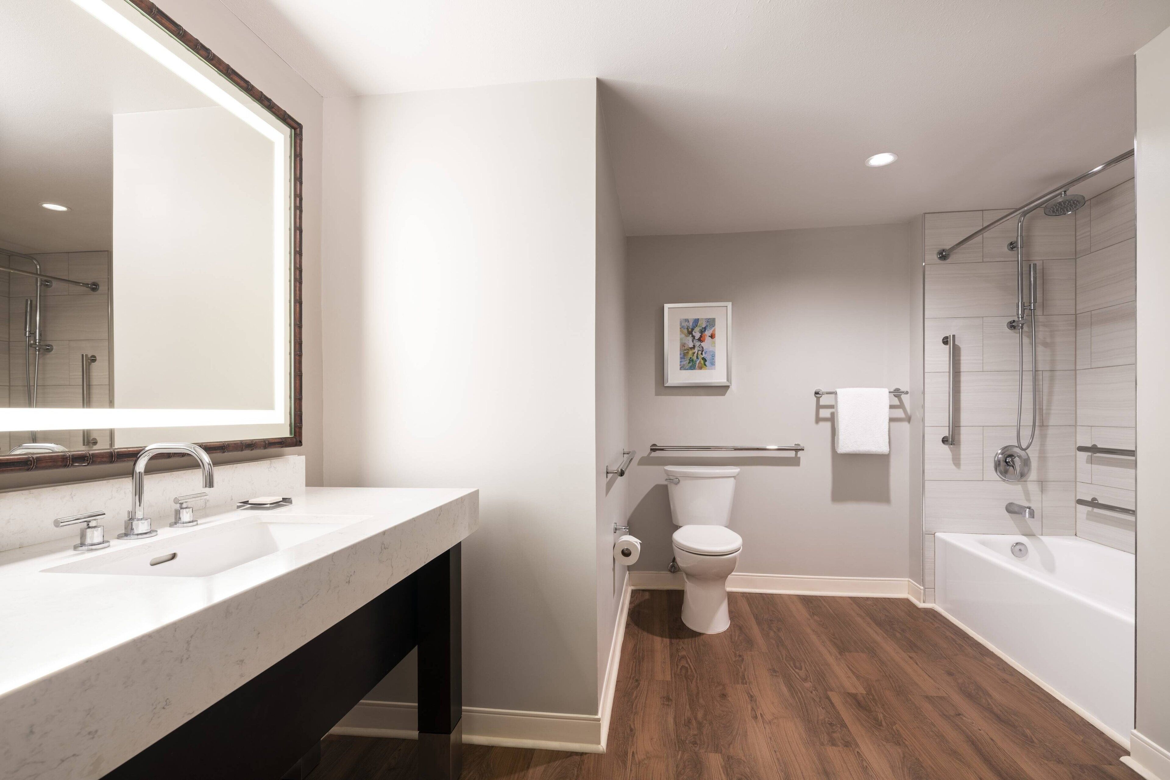 Een moderne badkamer met een grote spiegel, een wastafel, toilet en een bad.