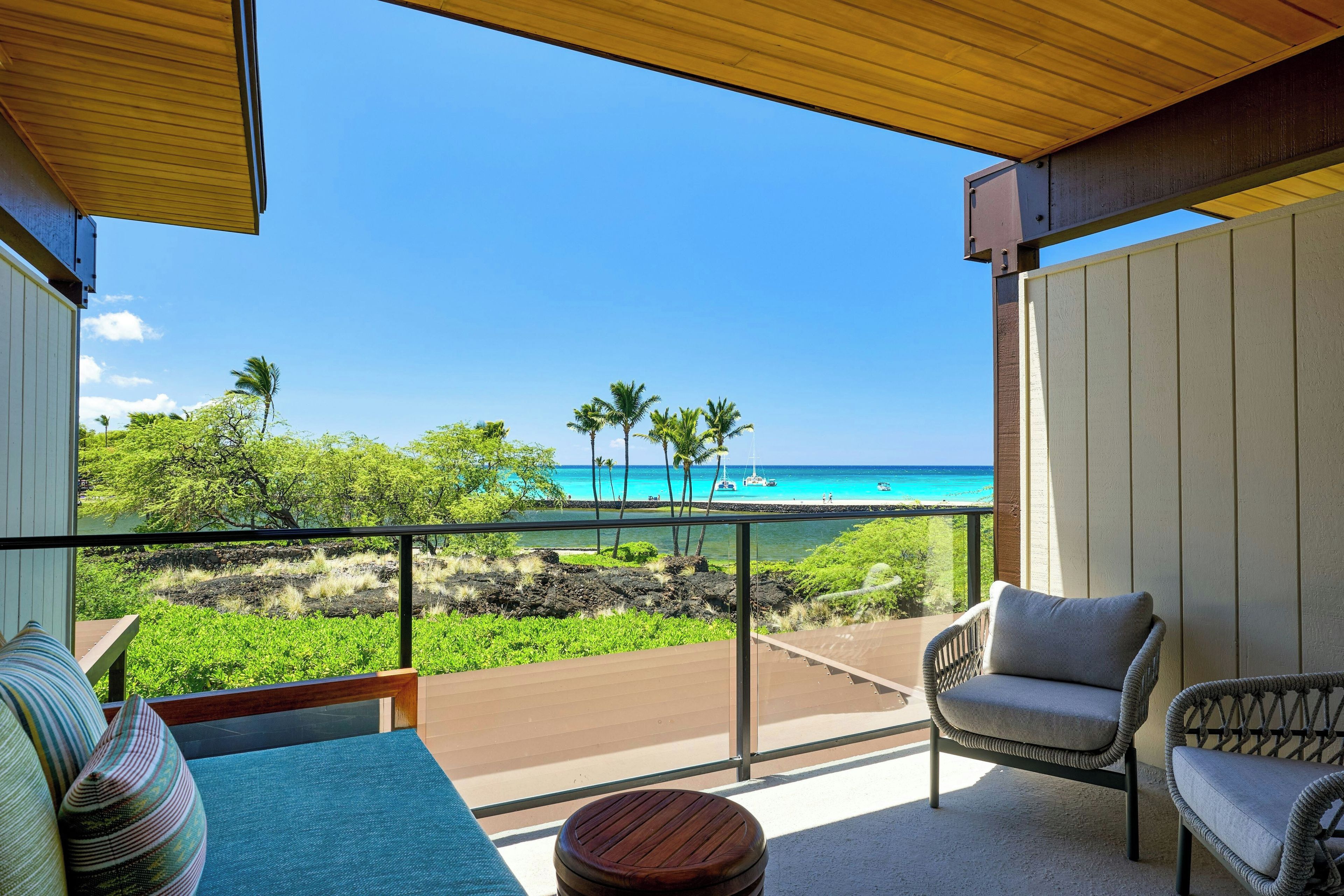 Un balcon avec vue sur l’océan, une chaise et une petite table.