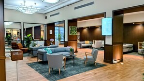 A modern hotel lobby with a reception desk, seating area, and a large screen displaying a message. - Mercure Paris Velizy (Velizy-Villacoublay)