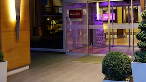Het uiterlijk van een Mercure hotel met een opvallend roze bord, glazen deuren en een moderne gevel.