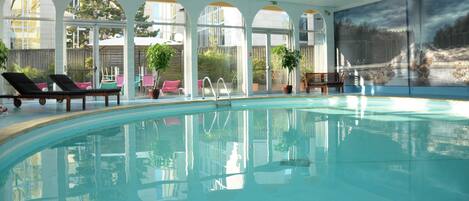 Una piscina techada, sillones reclinables de piscina