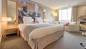 Een hotelkamer met een groot bed, een bureau, een stoel en een grote spiegel.