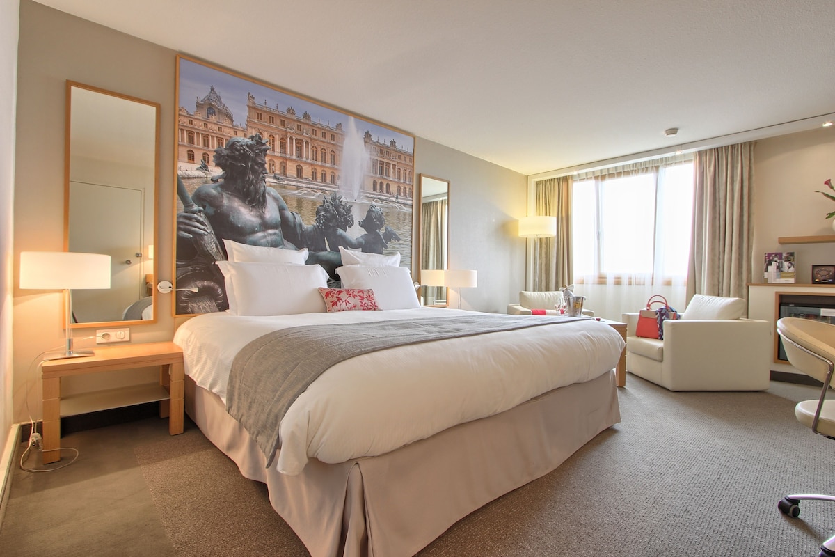 Une chambre d’hôtel avec un grand lit, un bureau, une chaise et un grand miroir.