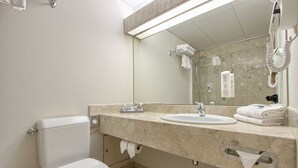 A bathroom with a toilet, sink, and a large mirror. - Mercure Paris Velizy (Velizy-Villacoublay)