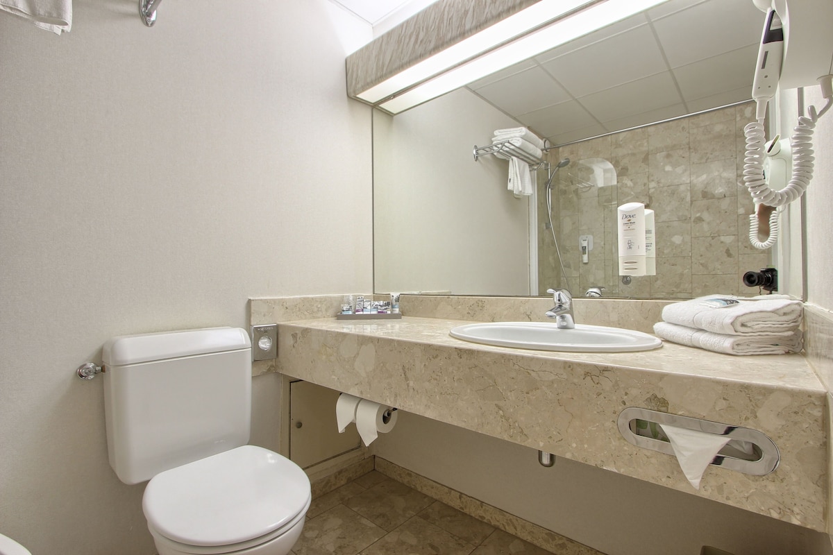 Une salle de bain avec des toilettes, un lavabo et un grand miroir.