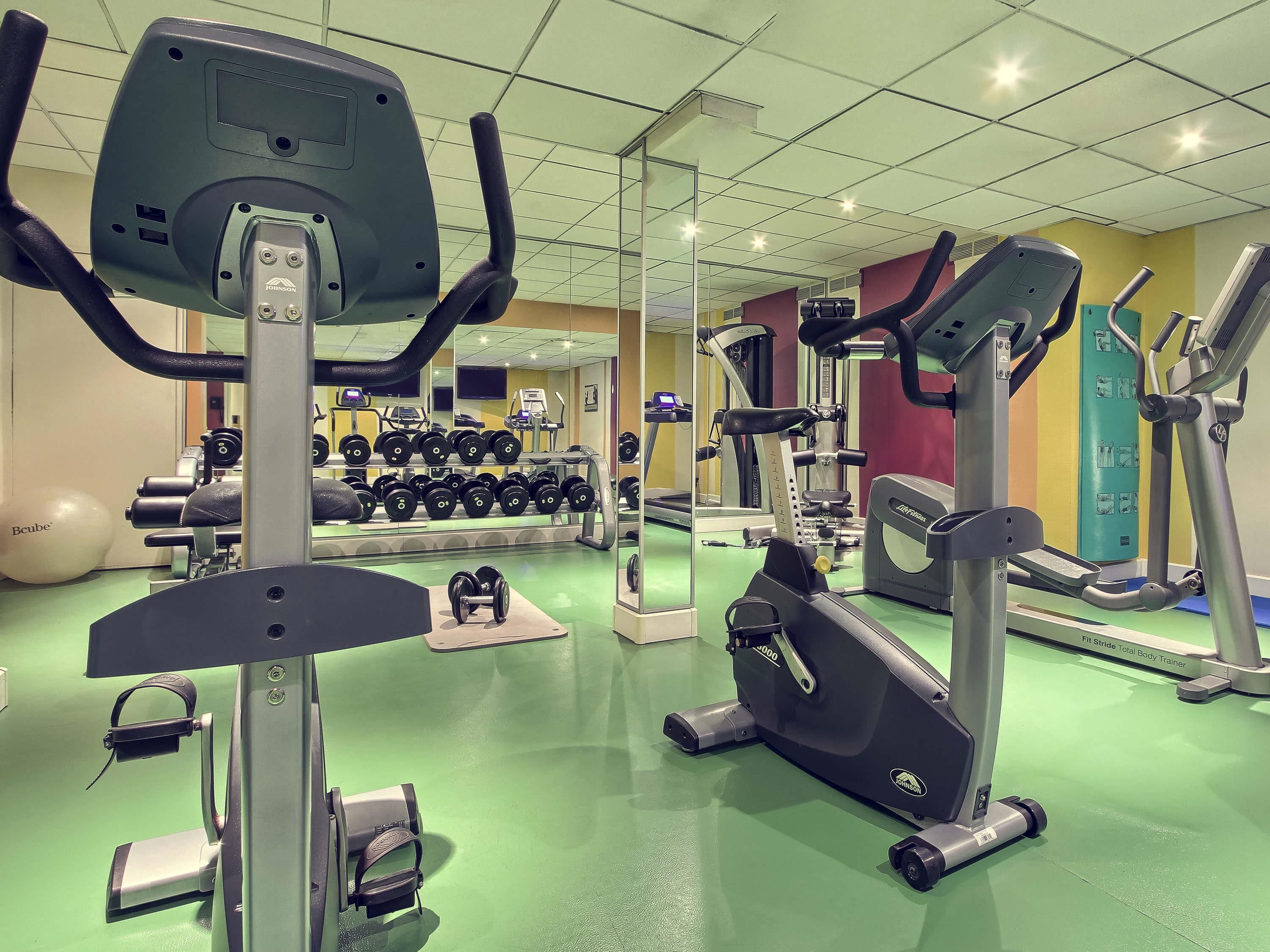 A gym with various exercise equipment including treadmills, elliptical machines, and free weights.