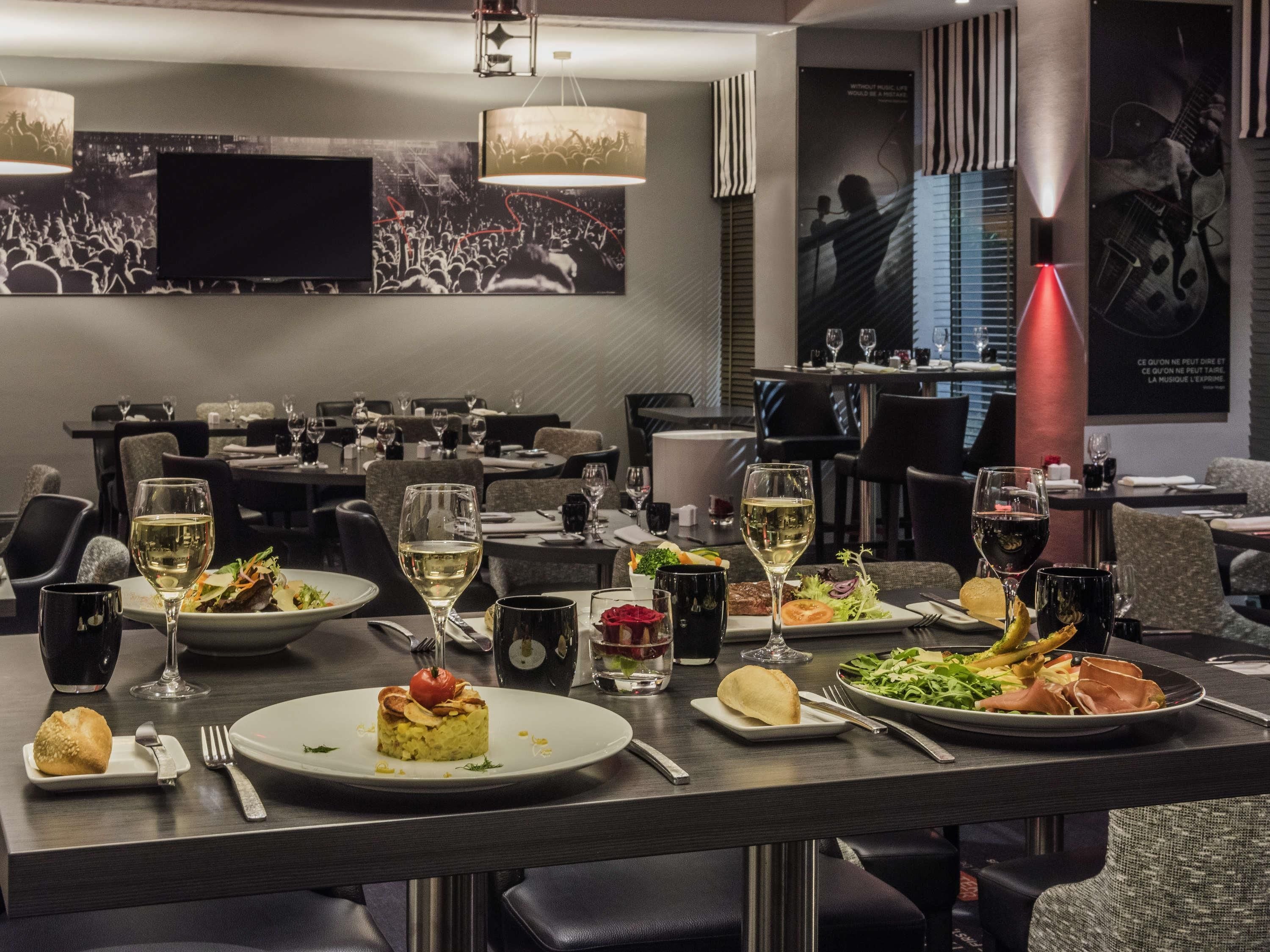 A restaurant with multiple tables set for dining, featuring various dishes and glasses of wine.