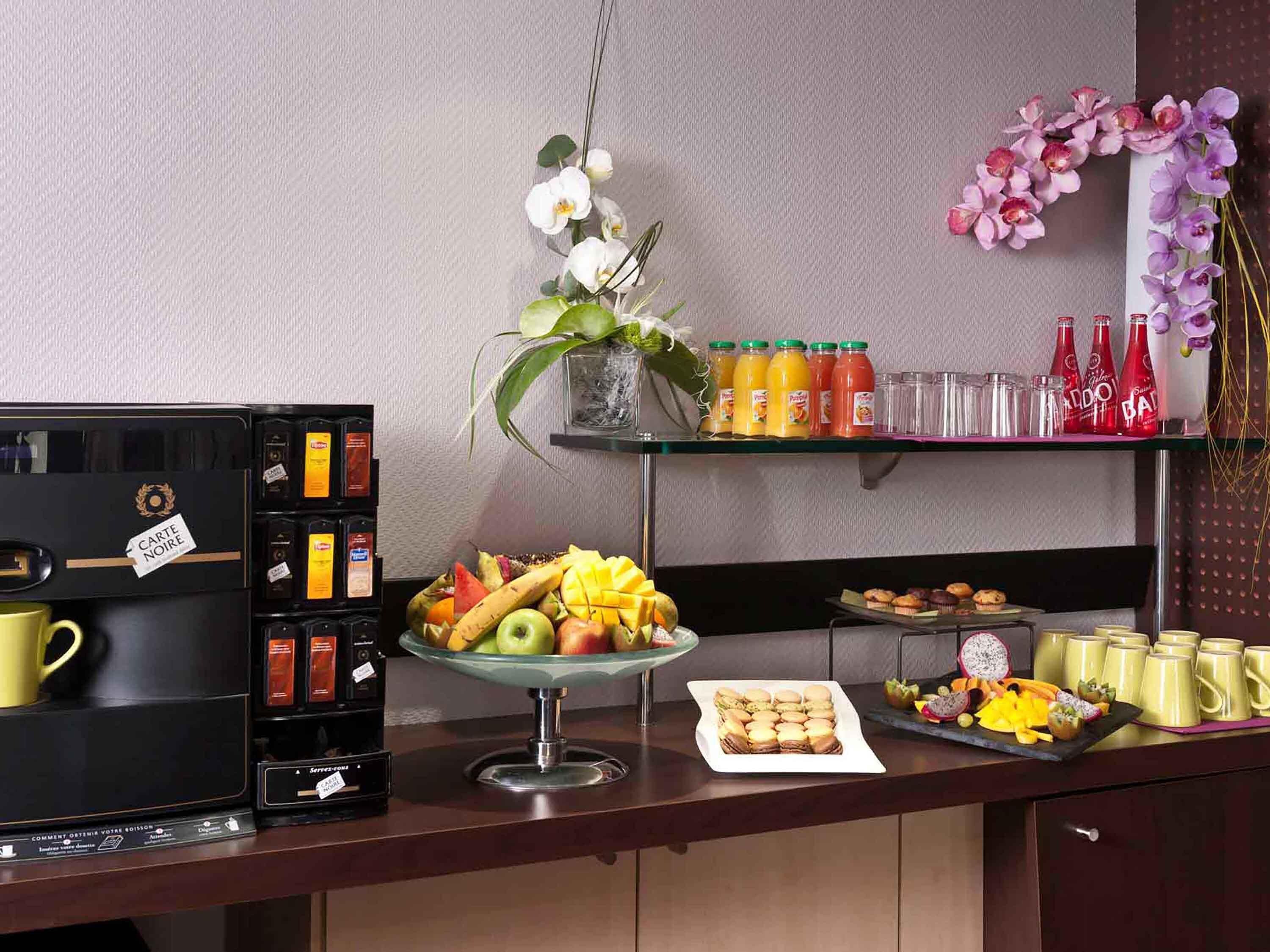 Un comptoir pour le petit-déjeuner avec des machines à café, un présentoir de fruits et des condiments.