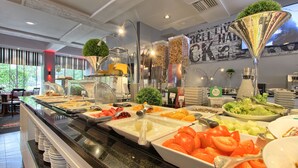 A buffet with various food items and a decorative plant in a glass container. - Mercure Paris Velizy (Velizy-Villacoublay)