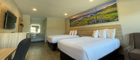 A hotel room with two beds, a desk, a chair, a TV, and a painting on the wall.